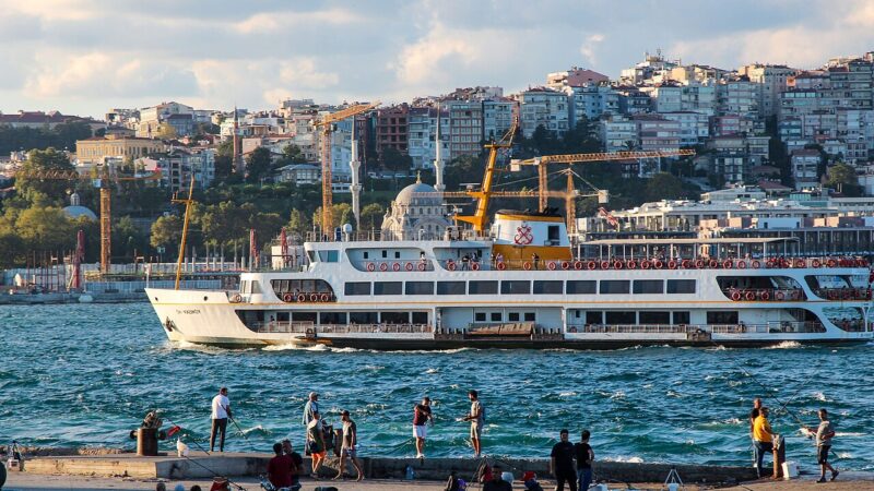 Istanbul ferry crossing the Bosphorus with fishermen in foreground